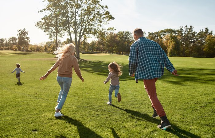 Familie rennt mit zwei Kindern über die Wiese