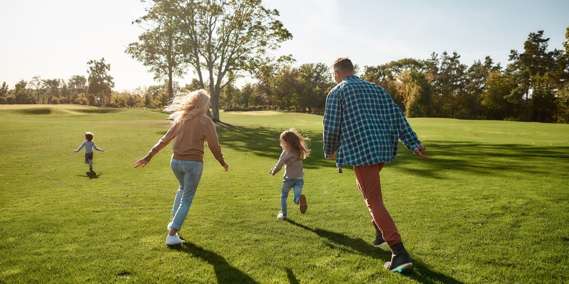 Familie rennt mit zwei Kindern über die Wiese