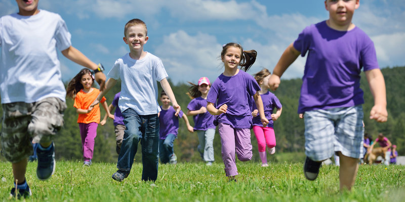 Eine Gruppe Kinder läuft uns lachend auf der Wiese entgegen
