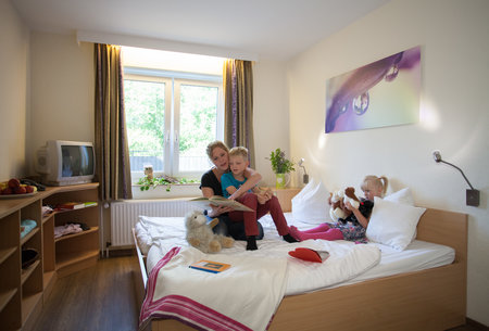 Ansicht Zimmer Kurklinik Gut Holmecke, Mutter mit zwei Kindern, lesen und spielen auf dem Bett